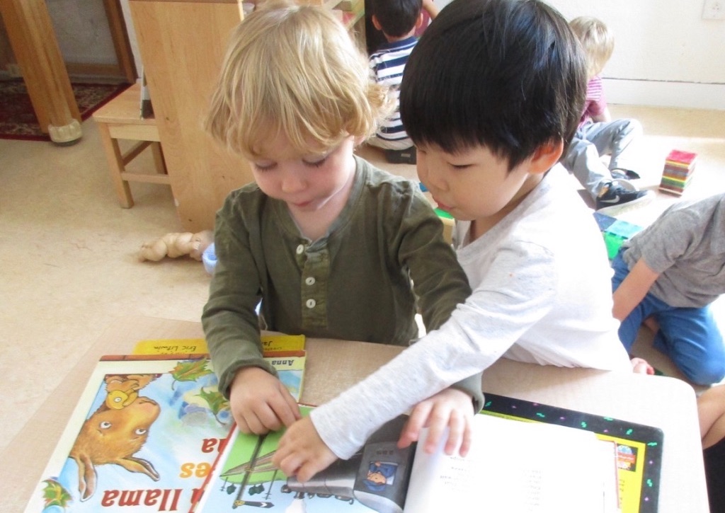 Children pointing at books and reading together