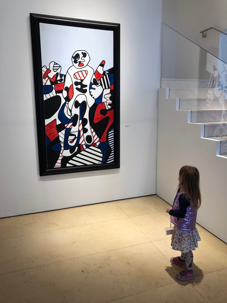 a child looking at a black, white and red impressionistic painting in a museum